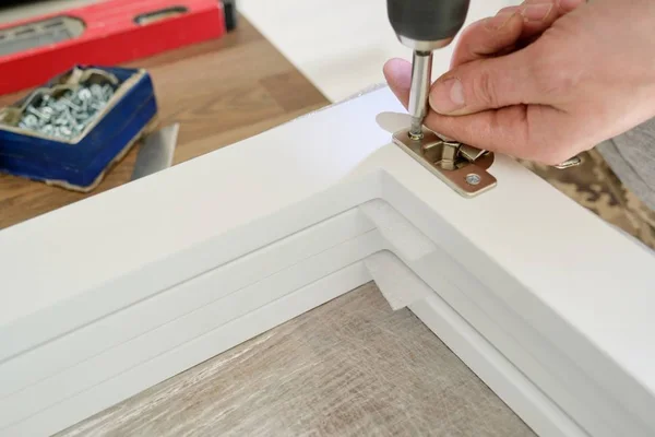 Möbler montering, närbild skruvning kromade dörrgångjärn med professionella verktyg — Stockfoto