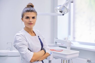Kolları bağlı, kendine güvenen genç bir dişçi kadın doktor.