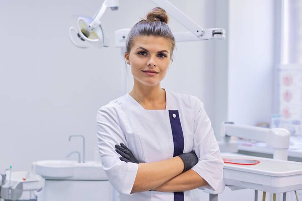 Portrait of young confident smiling dentist doctor woman, female with arms crossed