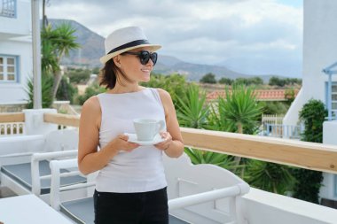 Bir fincan kahveyle rahatlama ve manzaranın tadını çıkaran bir kadın.