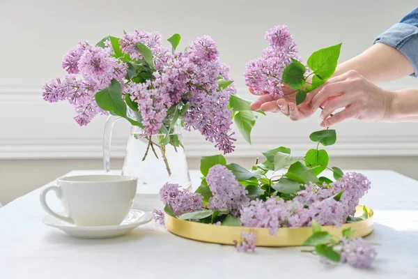 Manos de mujer con ramo de flores lila en jarra de vidrio — Foto de Stock