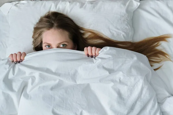 Rosto da jovem mulher bonita deitada no travesseiro na cama com cobertor — Fotografia de Stock