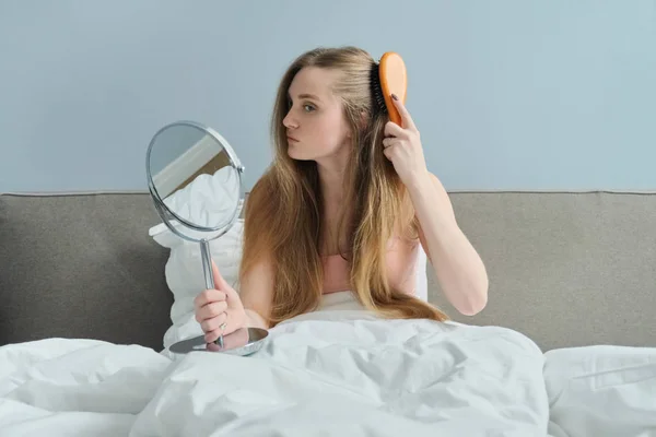 Menina bonita nova pentear cabelos longos com escova e espelho — Fotografia de Stock