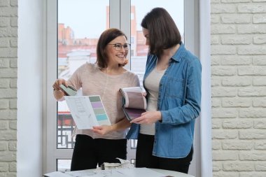 Kumaş örnekleriyle çalışan kadın tasarımcı ve istemci