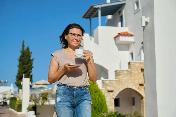 Outdoor portrait of mature beautiful woman walking with cup — 스톡 사진