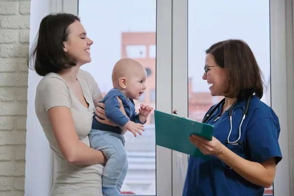 Doctor pediatrician talking with young mother holding her baby in her arms Royalty Free Stock Images