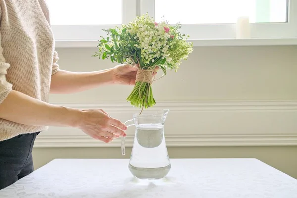 テーブルの上に花瓶の花の花束を持つ女性の手 — ストック写真