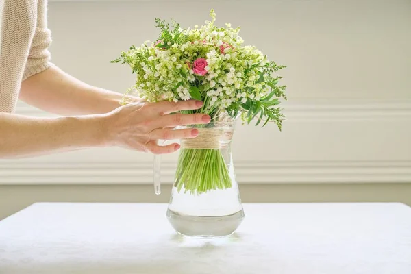 テーブルの上に花瓶の花の花束を持つ女性の手 — ストック写真