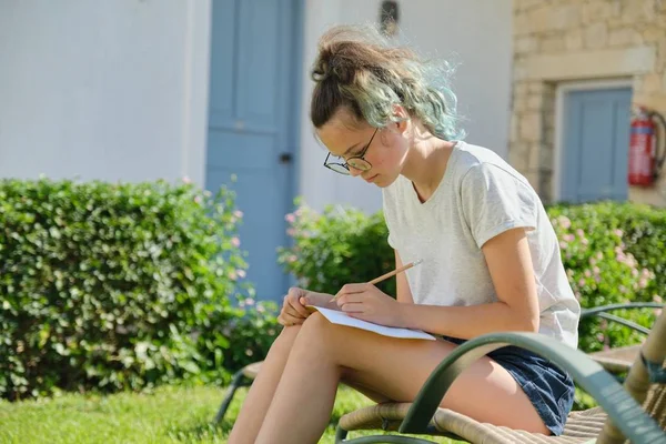 Student dívka 15, 16 let sedí venku, psaní ve škole notebook — Stock fotografie
