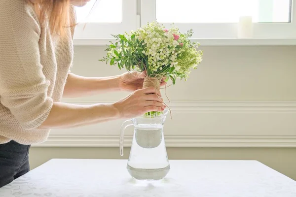 新鮮な春の花の花束、女性の手は花束を保持し、テーブルの上に花瓶に配置 — ストック写真