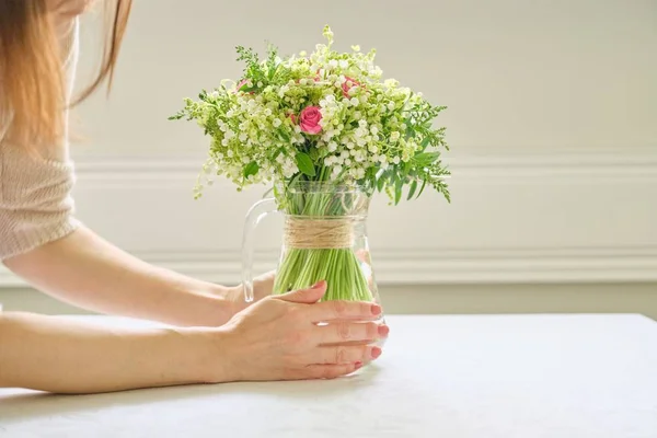 新鮮な春の花の花束、女性の手は花束を保持し、テーブルの上に花瓶に配置 — ストック写真