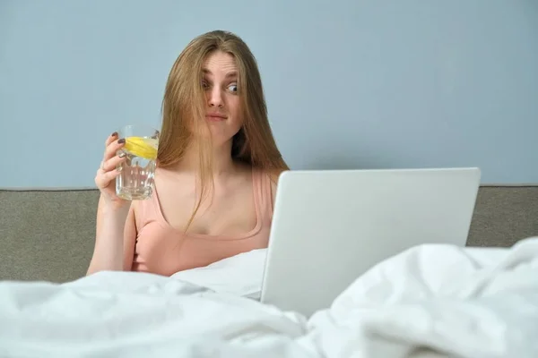 Vacker känslomässig kvinna sitter i sängen med bärbar dator — Stockfoto