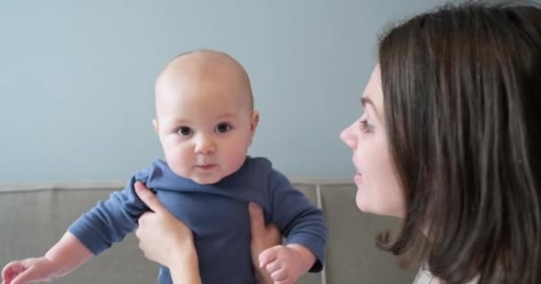 Уход за младенцем, мать воспитывает сына в руках, обнимает и целует — стоковое видео
