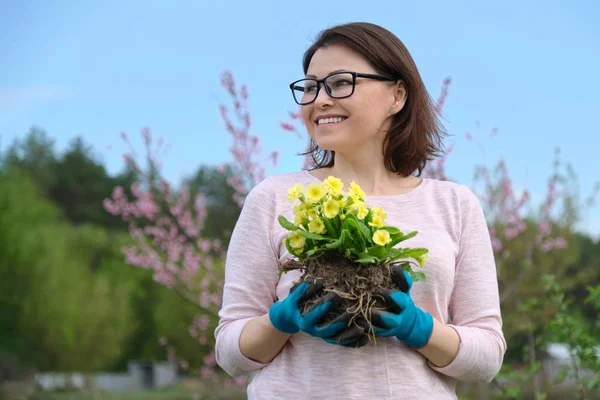 Voorjaar portret van vrouw in handschoenen met primrose bloemen in handen in de tuin — Stockfoto