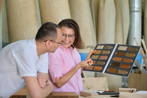 Man and woman choosing finish processing of wooden furniture — Stock Photo, Image