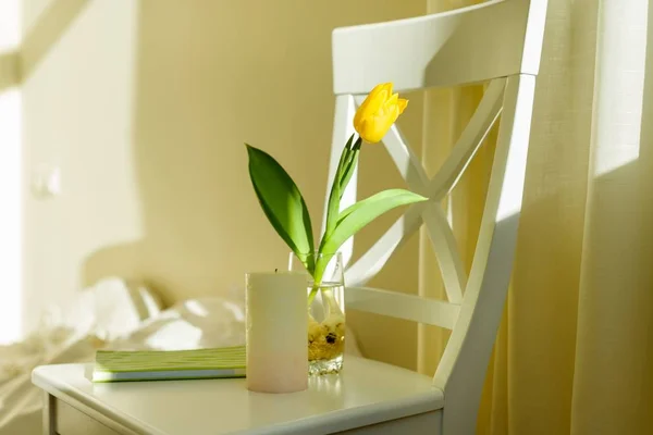 Flor de tulipa amarela em vidro com água na cadeira branca no interior do quarto — Fotografia de Stock