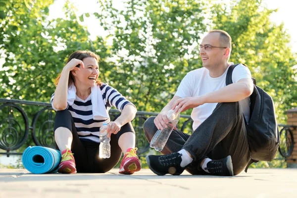 Happy smiling mature couple sitting in the park, talking resting after doing sports — 스톡 사진