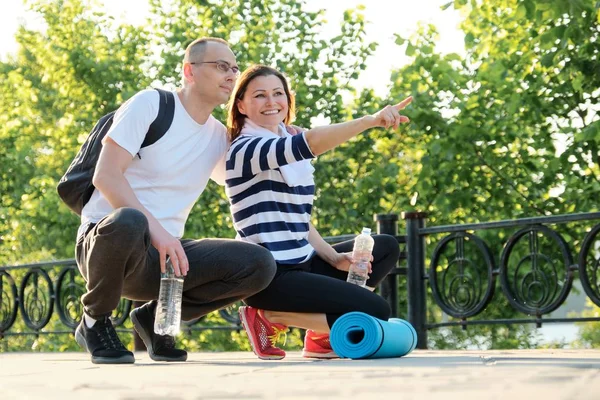 Happy smiling mature couple sitting in the park, talking resting after doing sports — Stock Photo, Image