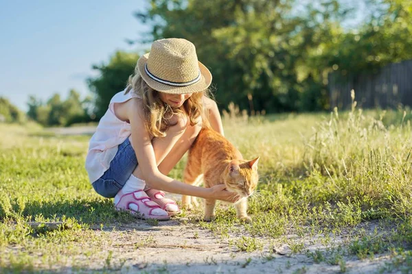 Flicka barn i hatt på landet väg leker med röd katt, solig sommardag rustik stil — Stockfoto