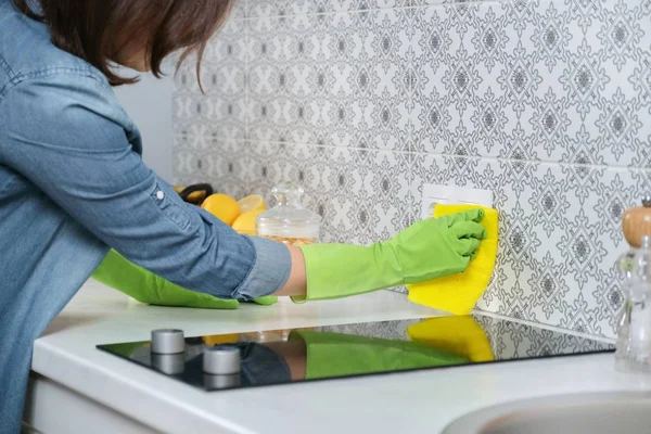 Vrouw in handschoenen met vodden schoonmaken huis in keuken — Stockfoto