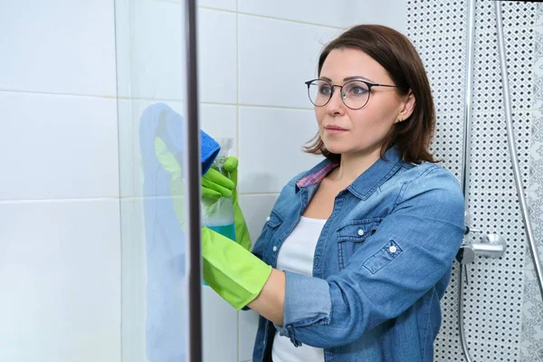 Cleaning bathroom, woman washing and polishing shower glass — Stockfoto