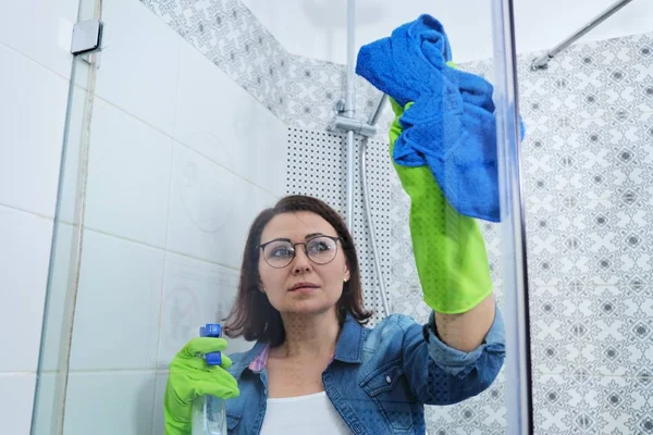 Cleaning bathroom, woman washing and polishing shower glass — 스톡 사진