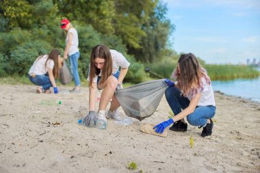 Öğretmenleri olan bir grup öğrenci plastik çöpleri temizliyor.