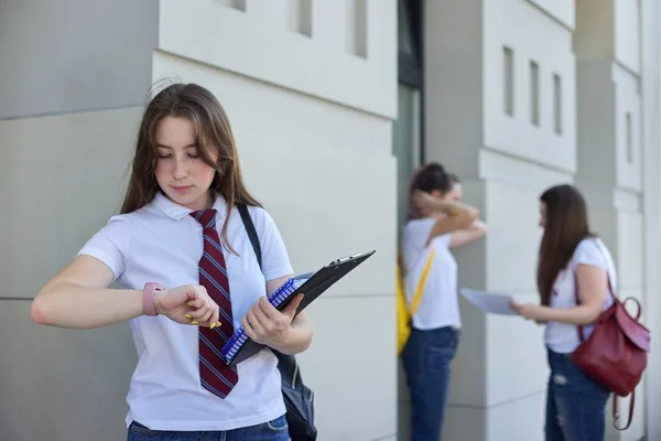 Meisje student kijkt naar polshorloge, college onderwijs, outdoor tieners studenten — Stockfoto