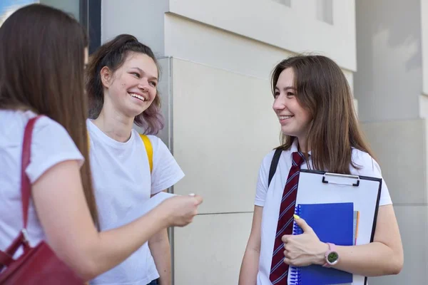 Konuşan öğrenci kızlar. Sırt çantalı üç genç, açık havada gülüyor ve konuşuyor.. — Stok fotoğraf