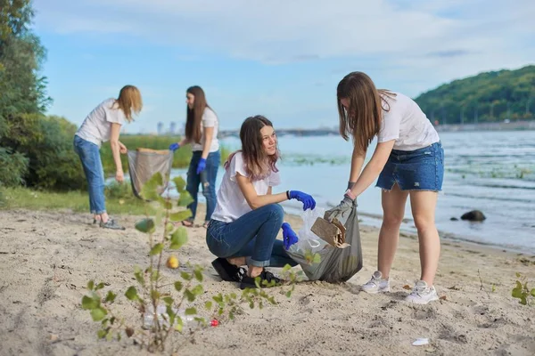 Nastolatki sprzątające plastikowe śmieci w naturze, brzeg rzeki — Zdjęcie stockowe