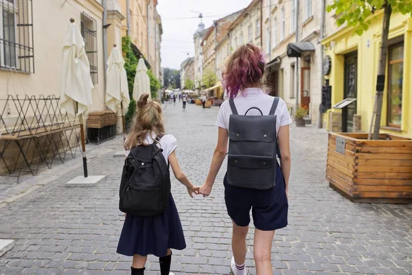 Children going to school, two girls sisters holding hands, back view — 图库照片