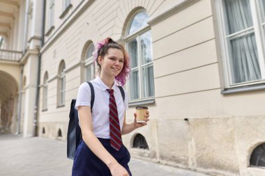 Girl student 15, 16 years old walking with backpack, cup of drink