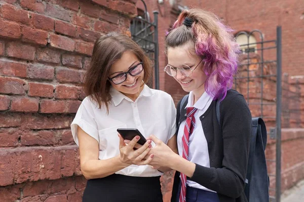 Estudiante mujer caminando y hablando con la profesora, chica mostrando en la pantalla del teléfono inteligente — Foto de Stock