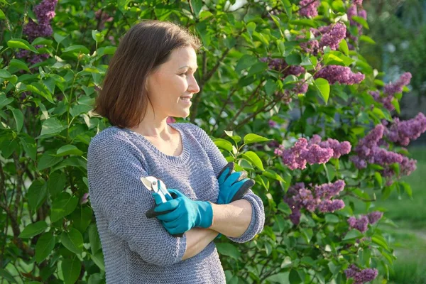 Портрет взрослой улыбающейся женщины-садовницы в садовых перчатках с секаторами — стоковое фото