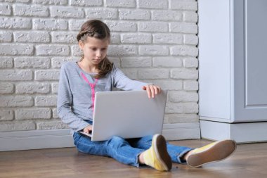 Modern technologies in peoples lives, girl child sitting at home with laptop computer