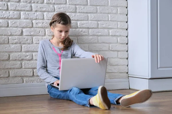 Tecnologie moderne nelle vite dei popoli, bambina seduta a casa con computer portatile — Foto Stock