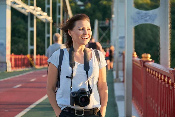 Mature female with backpack photo camera smiling on sunny summer day — Stock Photo, Image