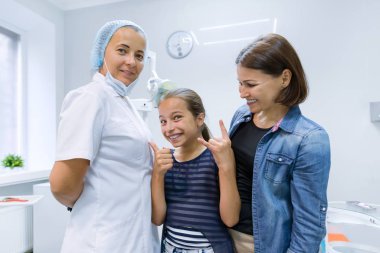 Happy mother and child in office with dentist doctor after dental treatment