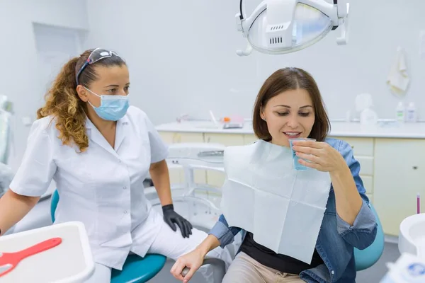 Жінка пацієнтка сидить у стоматологічному кріслі зі склянкою води — стокове фото