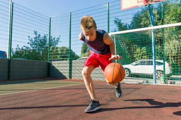 Chlapec teenager hraje basketbal v městském basketbalovém hřišti — Stock fotografie