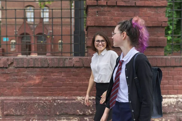 Дівчина студент підліток ходить і розмовляє з жінкою вчителькою — стокове фото