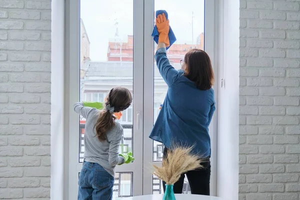 Madre e hija niño en guantes con trapo detergente limpiando ventanas juntas —  Fotos de Stock