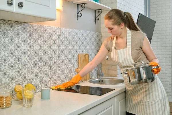 Молода жінка в фартухових рукавичках миття посуду з ганчіркою — стокове фото