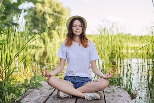 Chica adolescente sentada en posición de loto, meditando en la naturaleza —  Fotos de Stock