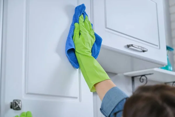 Vrouw in handschoenen met vodden reinigen, polijsten meubels op keuken — Stockfoto