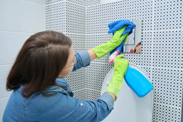 Mujer en guantes de limpieza y pulido botón de baño cromado en la pared de azulejos —  Fotos de Stock