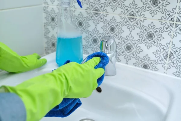 Kobieta mycie rąk i polerowanie umywalka i kran w łazience — Zdjęcie stockowe