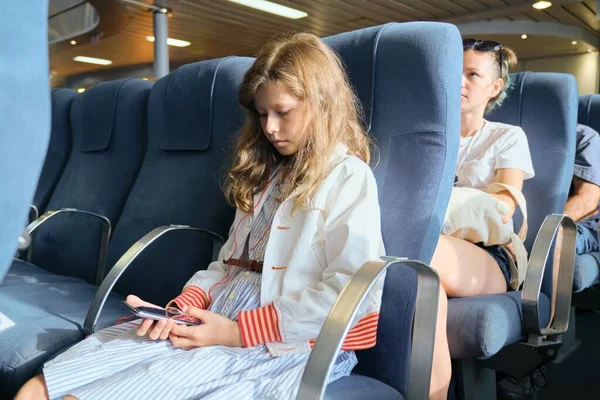 Κορίτσι παιδί χρησιμοποιώντας το smartphone, ενώ κάθεται μέσα στο πλοίο — Φωτογραφία Αρχείου