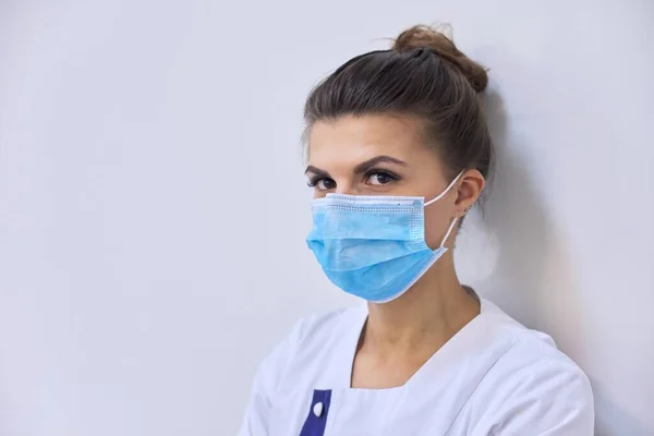 Joven mujer seria médico en máscara médica mirando a la cámara — Foto de Stock