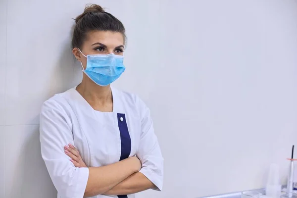 Joven mujer seria y confiada médico en máscara médica con los brazos cruzados — Foto de Stock